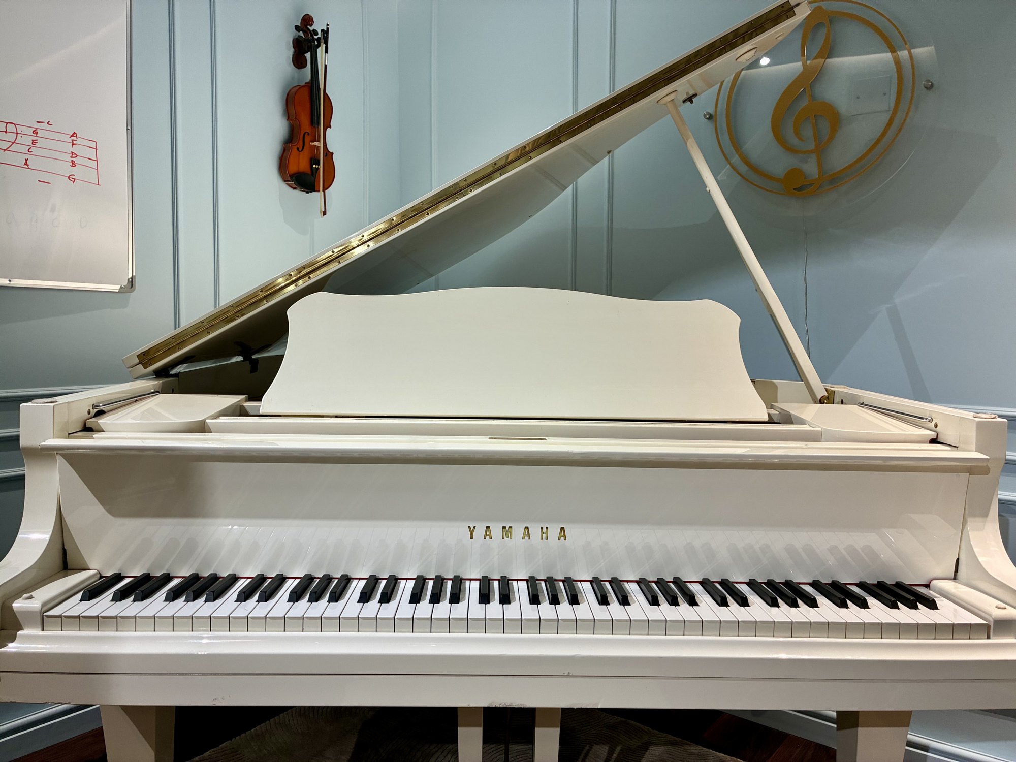 A white Yamaha grand piano in the Treble studio